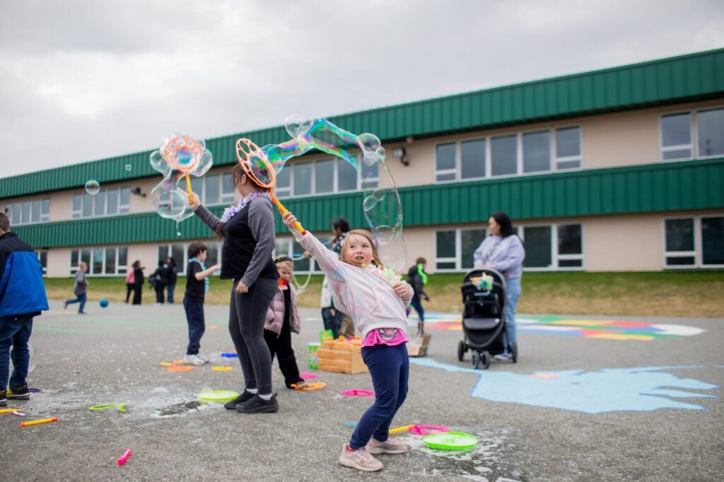 Elizabeth St. John, a second grader at Larson Elementary, plays with bubbles during the school's farewell luau on May 20, 2026.